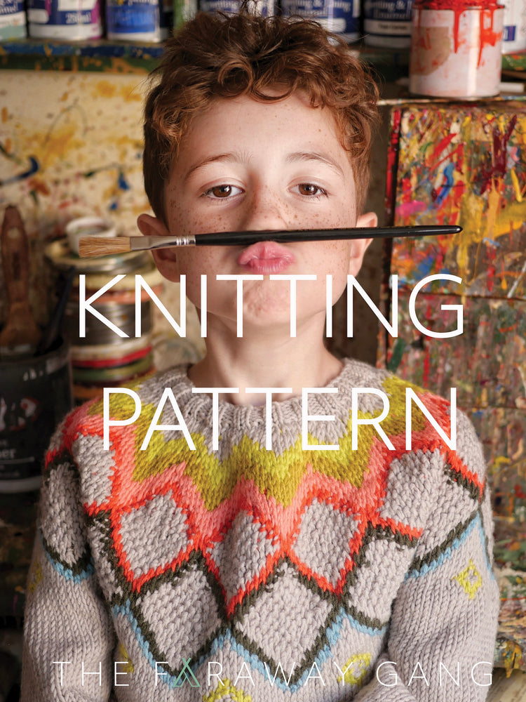 Child wearing a colorful knitted sweater with a paintbrush in front of their face, surrounded by art supplies.