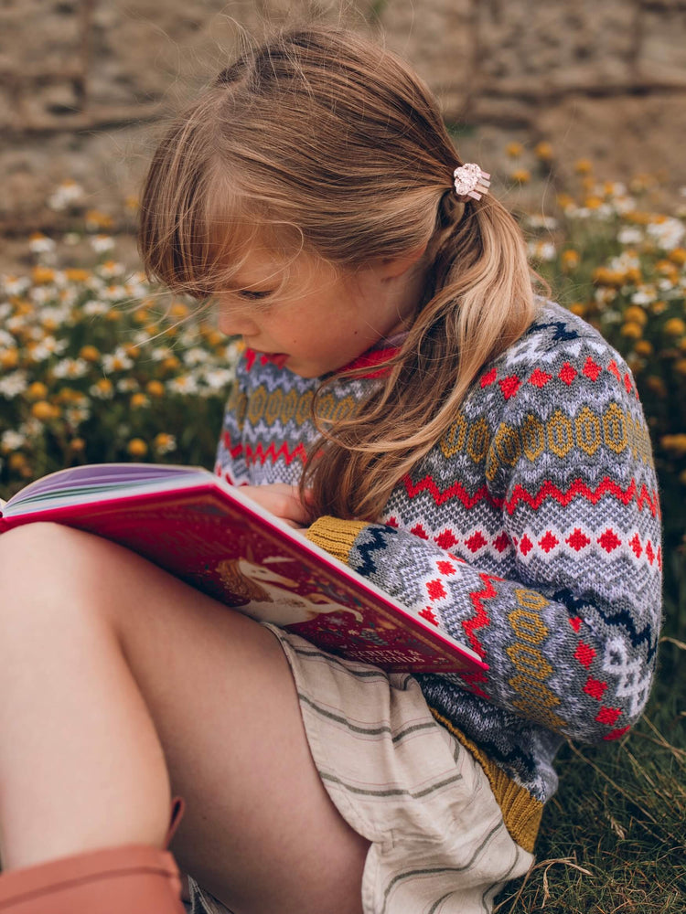 
            
                Load image into Gallery viewer, A young girl sitting on the ground reading a book while wearing The Faraway Gang&amp;#39;s &amp;#39;Daydreamer&amp;#39; Knitted Jumper.
            
        