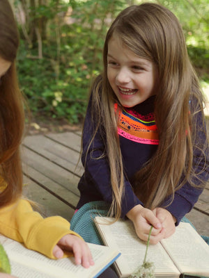 Girl laughing whilst holding a book The 'Creator' Children's Printed Sweatshirt.