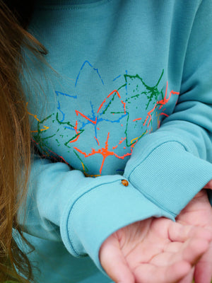 a child wearing The 'Rambler' Children's Printed Sweatshirt holding a ladybird.