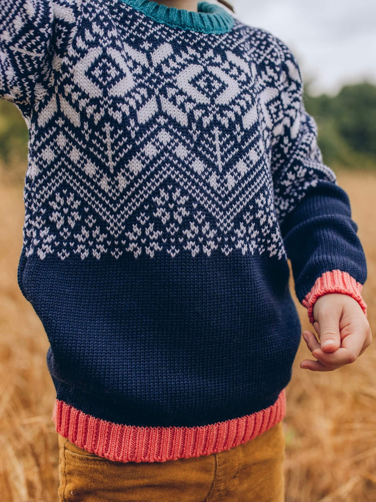 A child standing in a field wearing The Faraway Gang's 'Storyteller' Jumper.