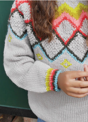 Grey hand - knit sweater with colorful heart pattern worn by a child