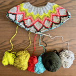 Knitted multicolored garment with yarn balls on a wooden surface