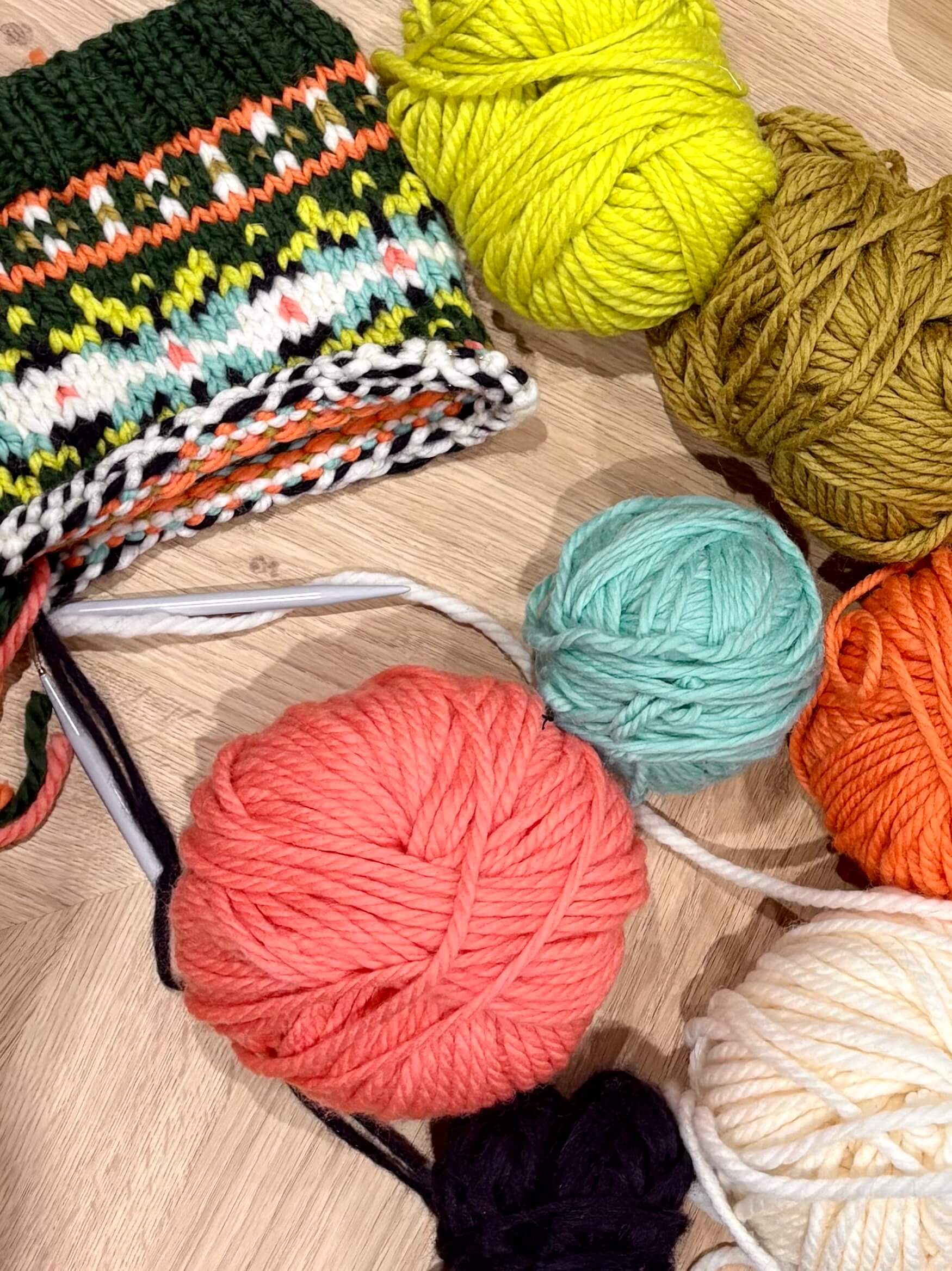 Colorful yarn balls and a crochet hook on a wooden surface