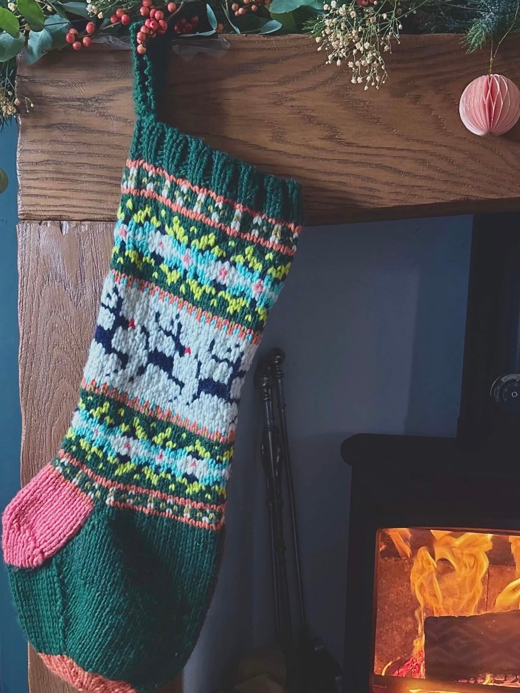 Colorful knitted Christmas stocking on a wooden mantel with a fireplace in the background.