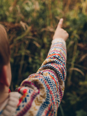 A young boy is wearing 'Explorer' Knitted Jumper by The Faraway Gang and pointing