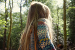 A little girl standing in the woods looking up wearing 'The Storyteller' Knitted Jumper by The Faraway Gang.