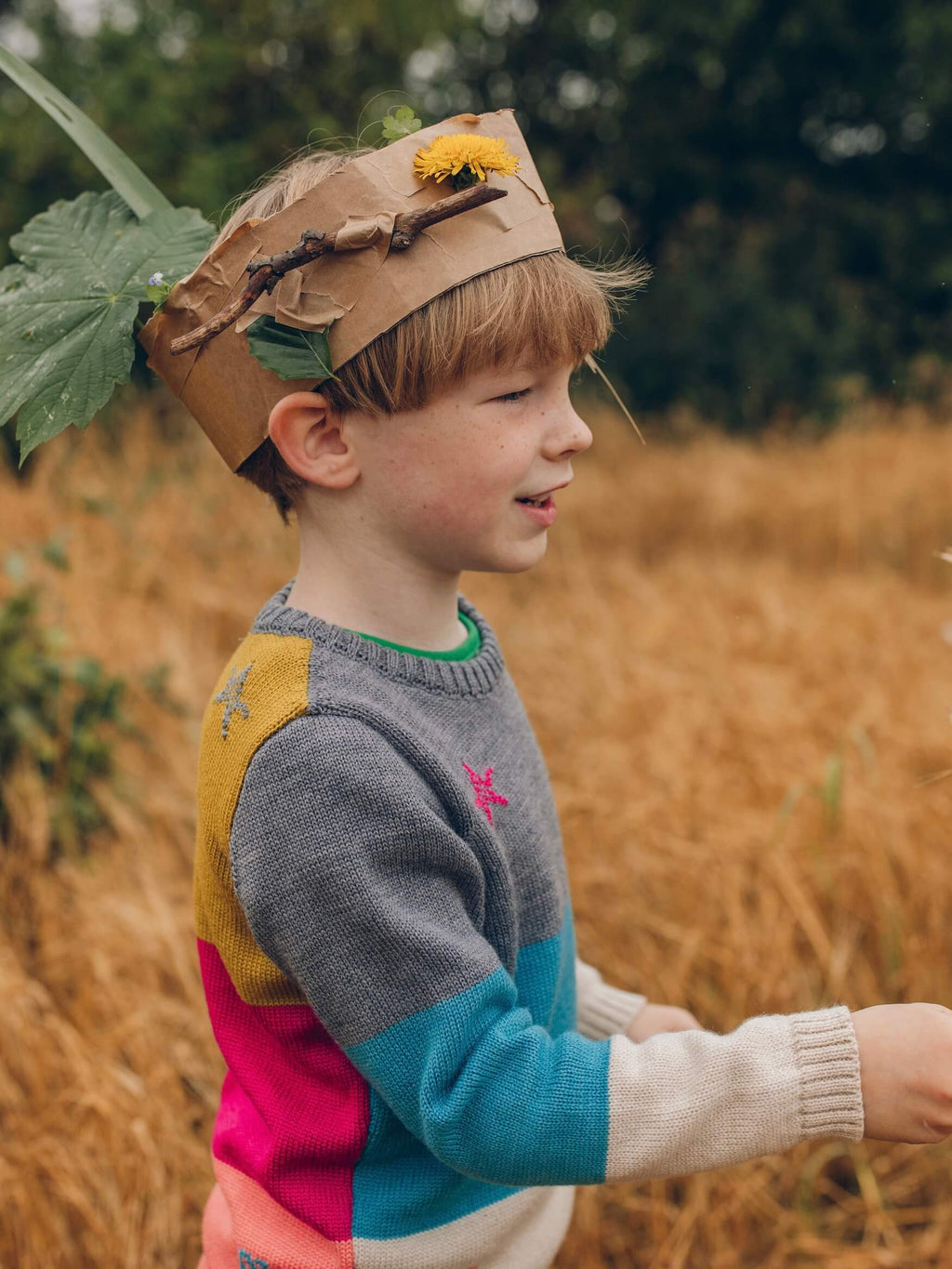 A young boy wearing The Faraway Gang's 'Stargazer' Knitted Jumper wearing a cardboard crown.