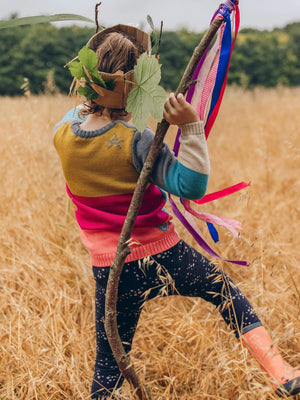 A little girl dancing in a field of tall grass wearing The Faraway Gang's 'Stargazer' Knitted Jumper.