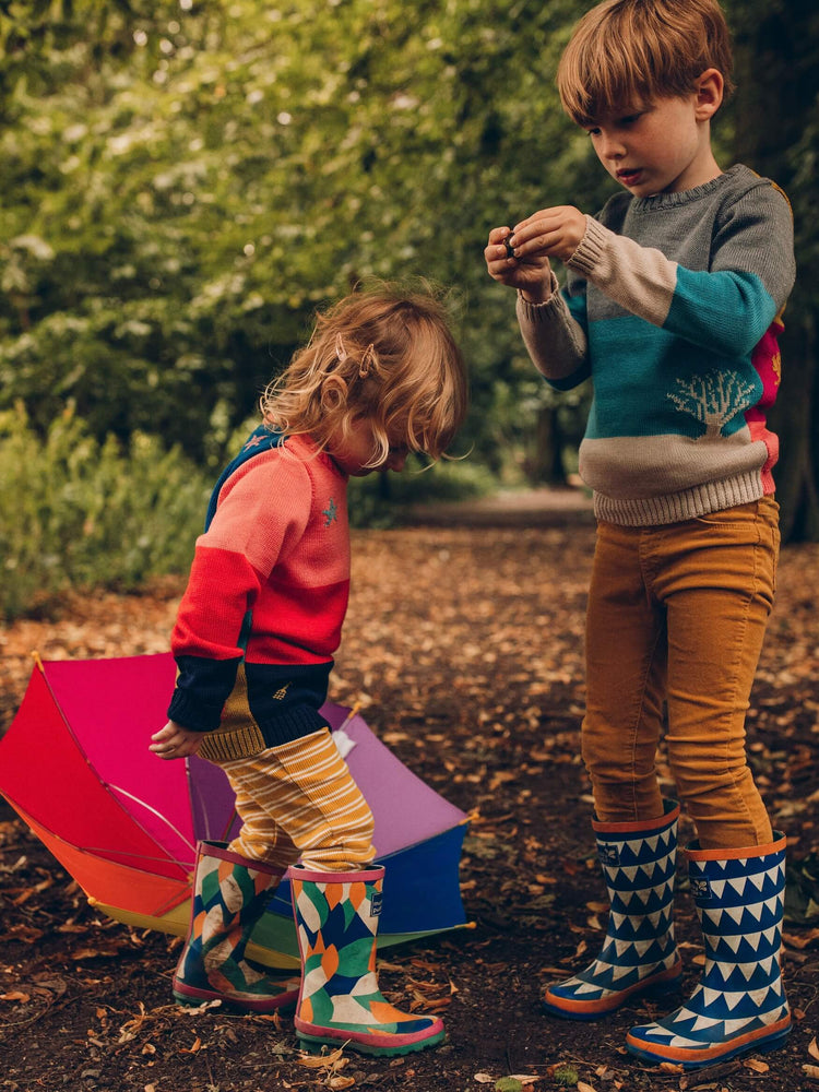 A boy and a girl standing next to each other with umbrellas wearing 'Stargazer' Knitted Jumpers from The Faraway Gang.