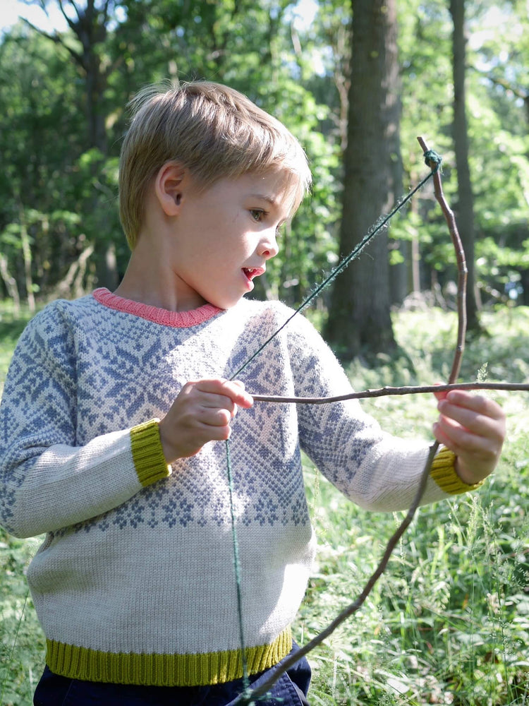 
            
                Load image into Gallery viewer, A young boy holding a homemade bow and arrow made from sticks wearing The &amp;#39;Storyteller&amp;#39; Knitted Jumper by The Faraway Gang.
            
        