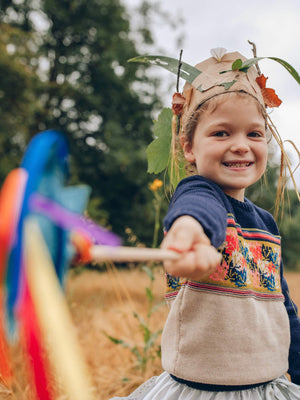
            
                Load image into Gallery viewer, A little girl holding a wand with ribbons and a star on it wearing The Faraway Gang&amp;#39;s &amp;#39;Adventurer&amp;#39; Knitted Jumper in a field.
            
        