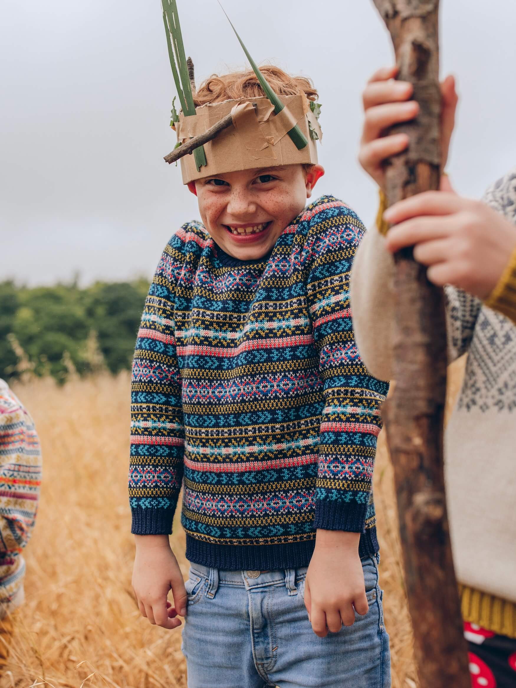 A young boy is wearing 'Explorer' Knitted Jumper by The Faraway Gang and looking cheeky.