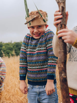 A young boy is wearing 'Explorer' Knitted Jumper by The Faraway Gang and looking cheeky.