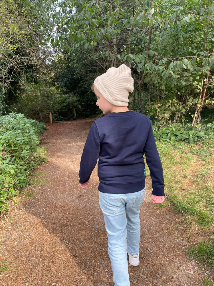 
            
                Load image into Gallery viewer, Child wearing the Fisherman hat in cream walking through the woods.
            
        