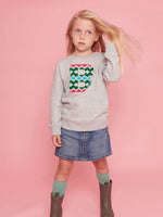 a little girl wearing a 'Narrator' Sweatshirt by The Faraway Gang and boots.