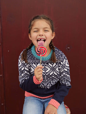 
            
                Load image into Gallery viewer, A little girl standing in the woods looking up wearing &amp;#39;The Storyteller&amp;#39; Knitted Jumper by The Faraway Gang licking a lolly pop..
            
        