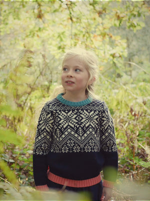 A little girl standing in the woods looking up wearing 'The Storyteller' Knitted Jumper by The Faraway Gang.