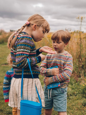 A boy and girl are wearing unisex fairilse jumpers by The Faraway Gang.