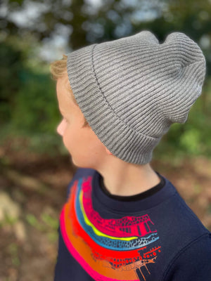 Child wearing the Fisherman hat in grey walking through the woods.